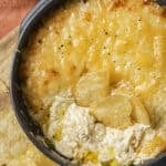 baked french onion dip in a cast iron pan with chips dipped into it
