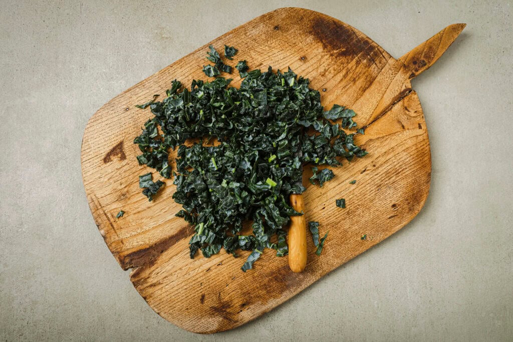 chopped kale on a wooden cutting board
