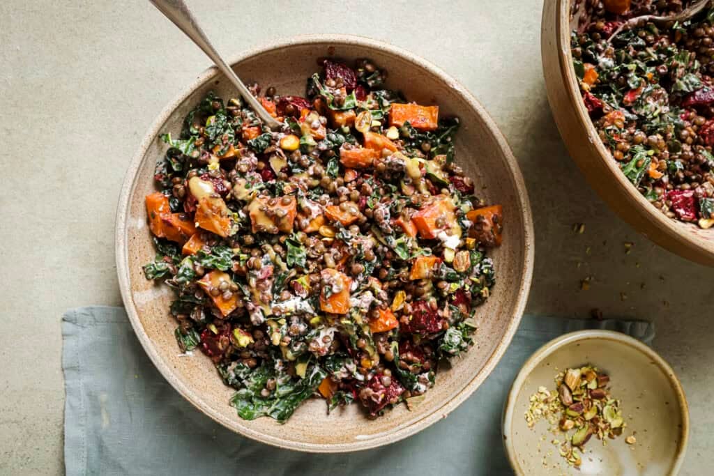 roasted beet and lentil chopped salad in a tan bowl with a spoon in it