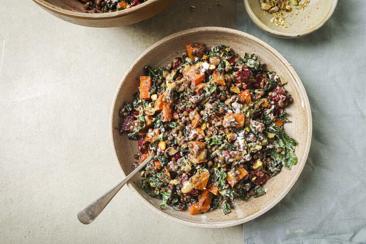 roasted beet and lentil chopped salad in a tan bowl with a spoon in it