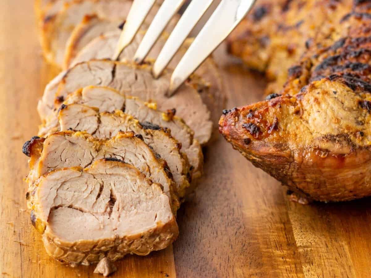 Three quarter view of a fork grabbing a slice of air fryer pork tenderloin